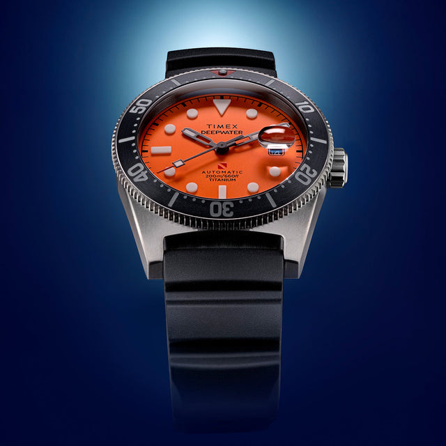 Close-up view of the Timex Deepwater Reef 200 showing its vivid orange dial, bold white markers, black bezel, and black rubber strap.