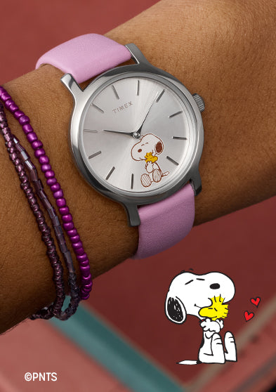 Peanuts® x Timex Transcend Snoopy Hug watch worn on wrist, featuring a silver dial with Snoopy hugging Woodstock and a soft pink leather strap.
