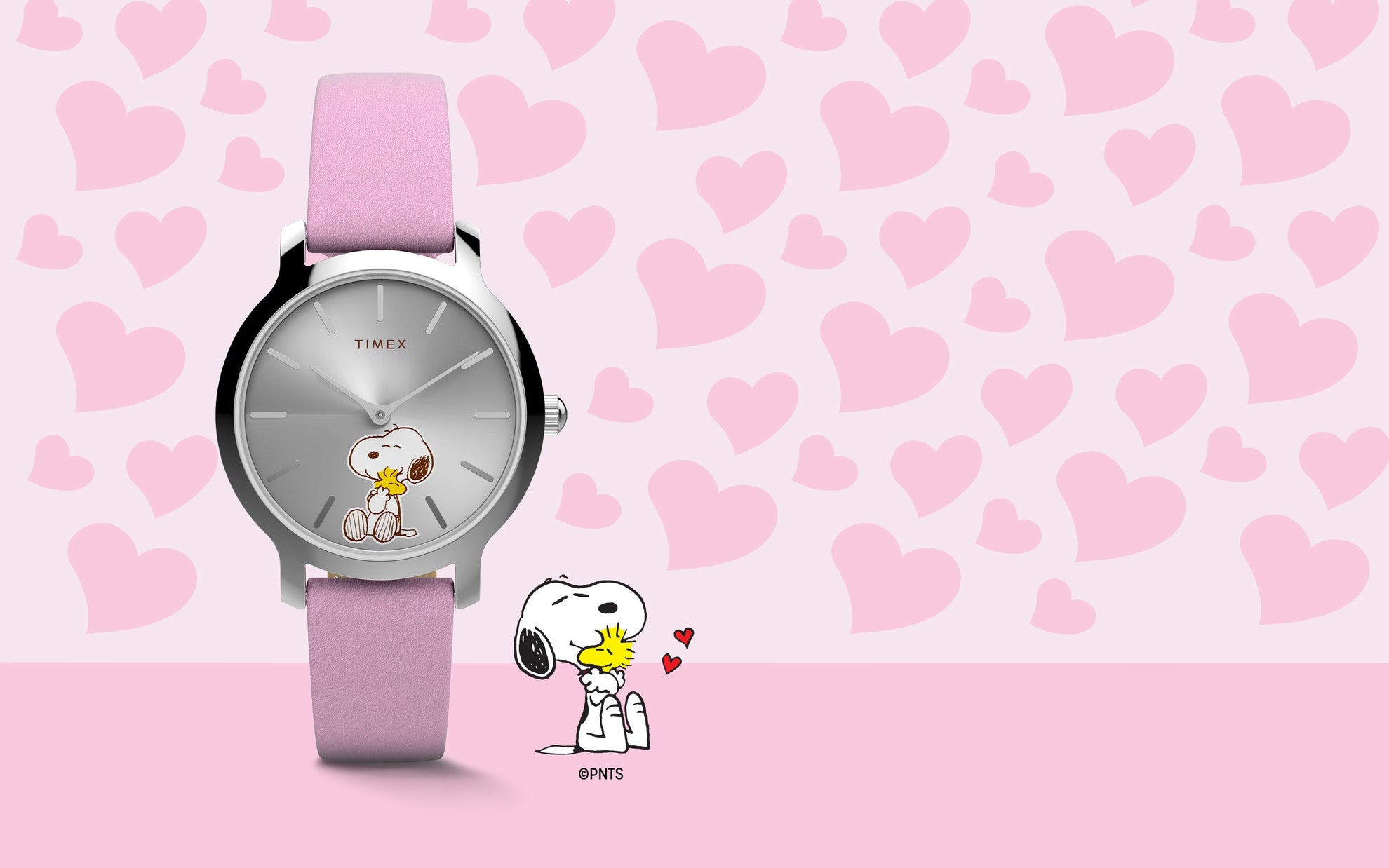 Peanuts® x Timex Transcend Snoopy Hug watch with a silver sunray dial, pink leather strap, and Snoopy hugging Woodstock on the dial, shown against a pink heart background.