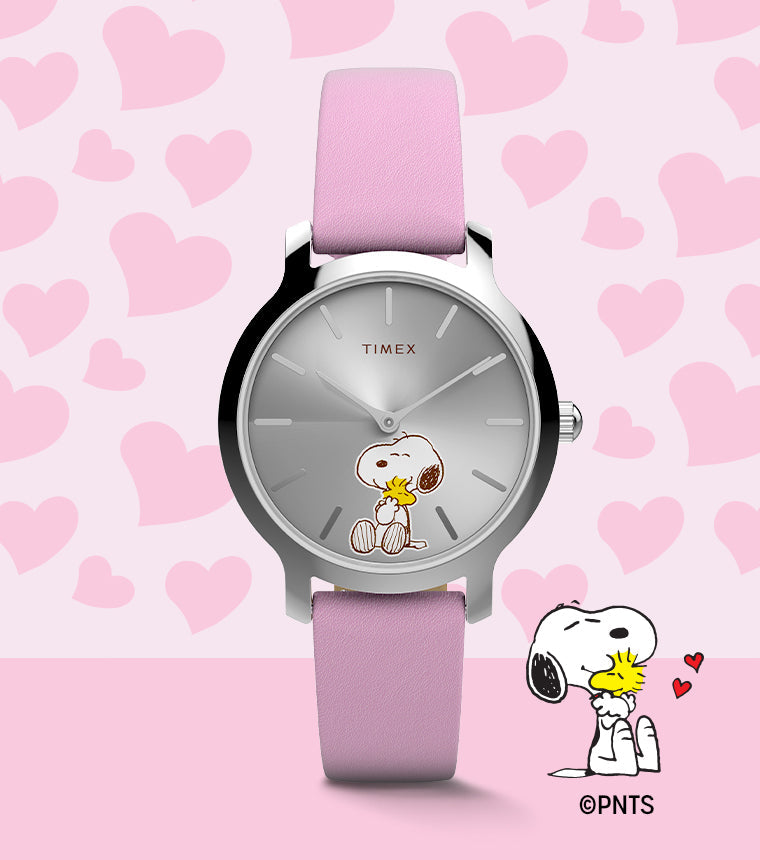 Peanuts® x Timex Transcend Snoopy Hug watch with a silver sunray dial, pink leather strap, and Snoopy hugging Woodstock on the dial, shown against a pink heart background.