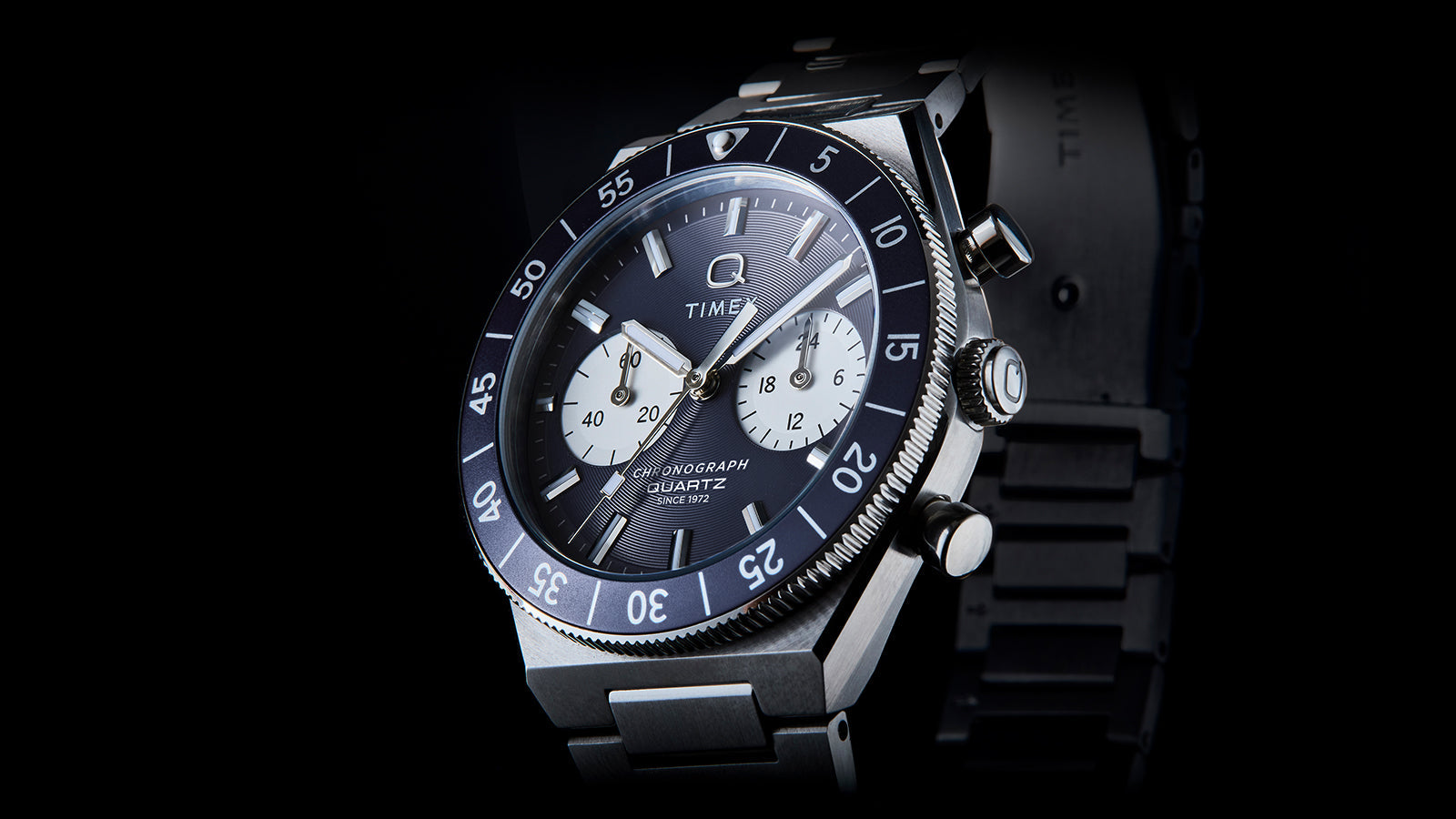 Angled close-up of the Q Timex Continental Chronograph highlighting the blue dial, black rotating bezel, and chronograph pushers.