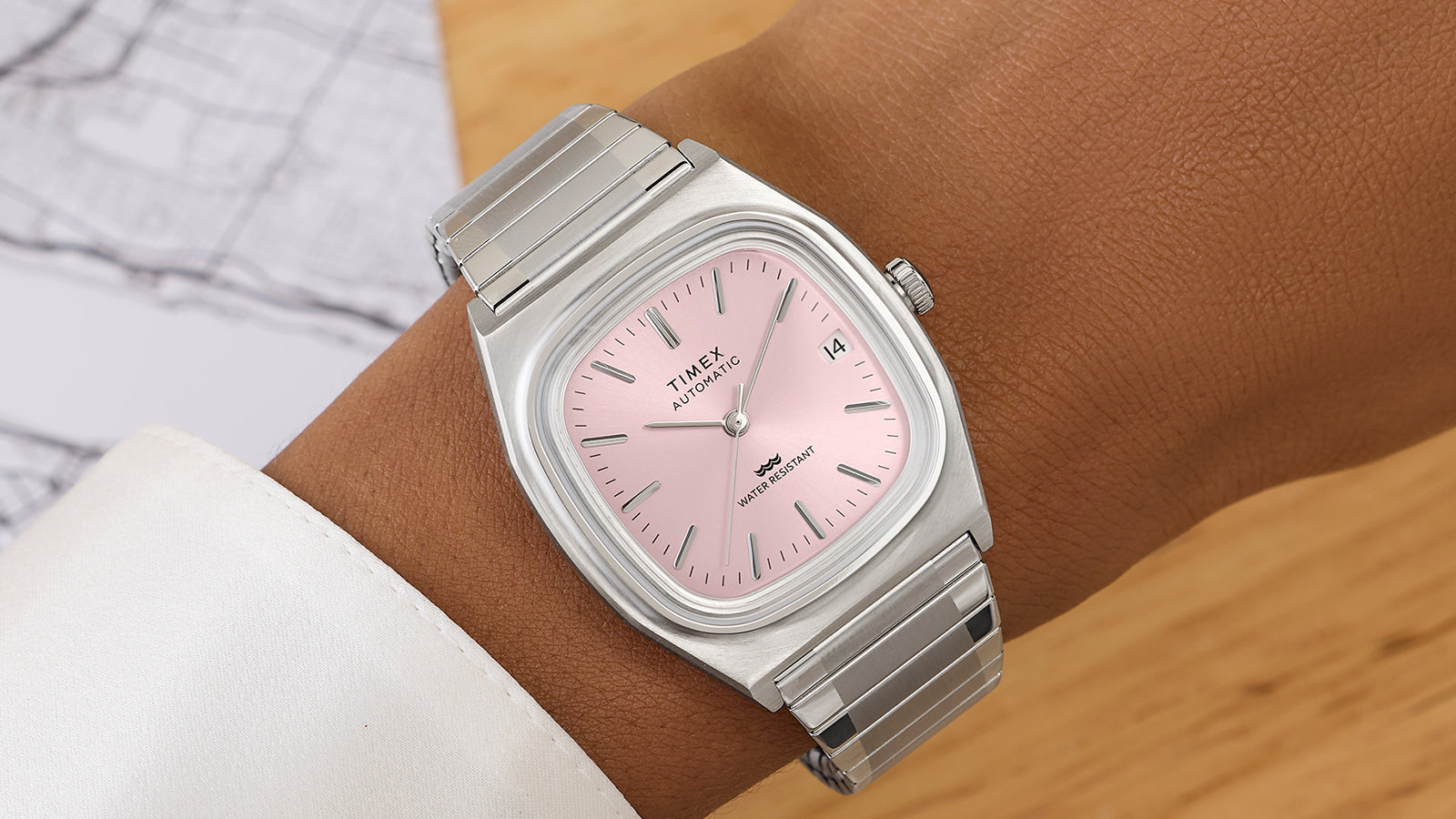 Timex® Automatic 1983 E Line stainless steel watch with light pink dial worn on wrist, showcasing the square case and metal expansion bracelet.