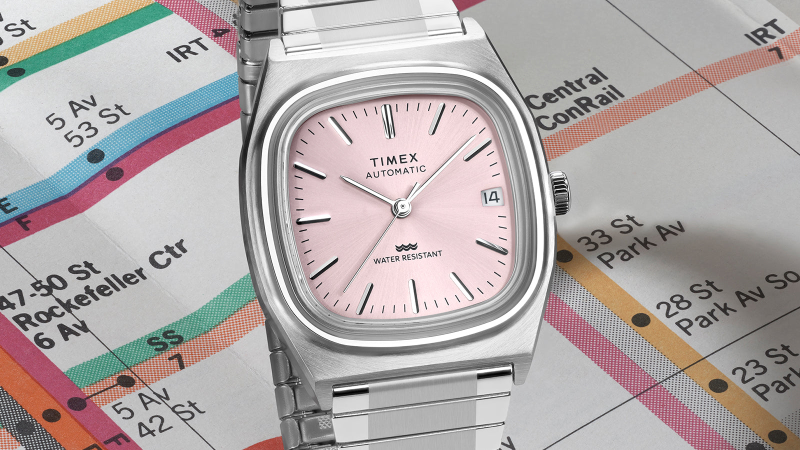 Close-up detail of the Timex® Automatic 1983 E Line pink sunray dial with silver-tone hour markers and date window at 3 o’clock.