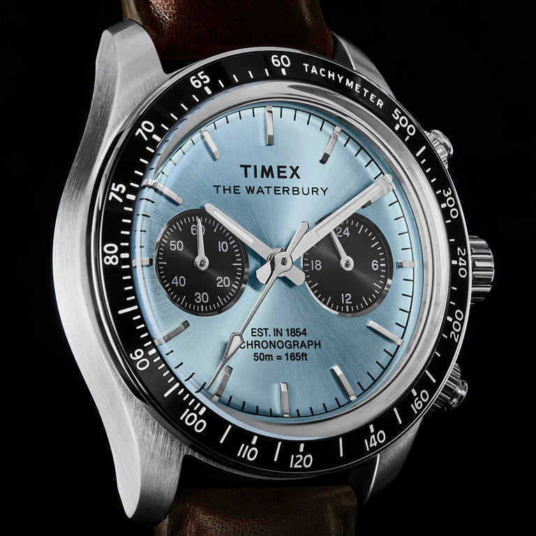 Angled close-up of Timex Waterbury Heritage Chronograph featuring a light blue sunray dial, dual subdials, and tachymeter bezel.