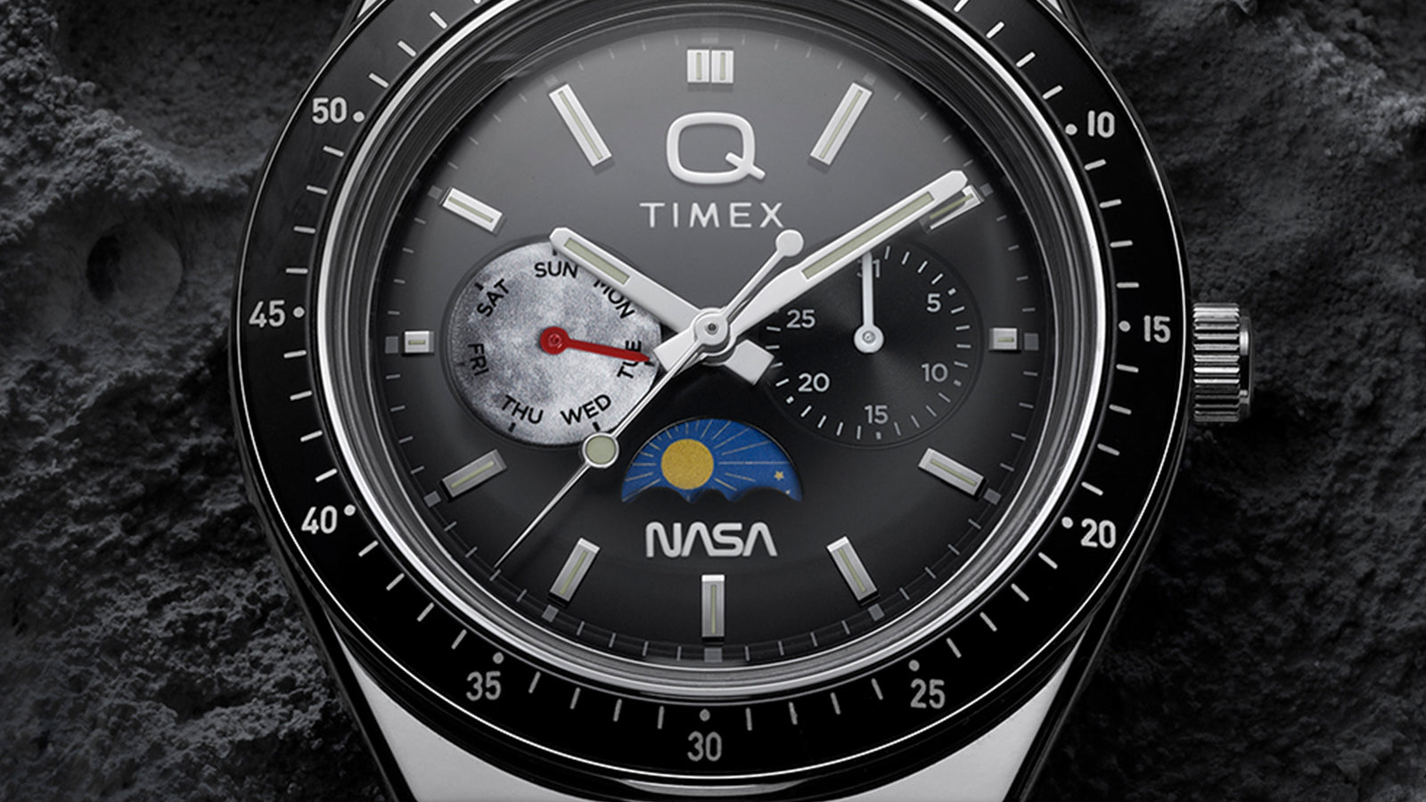 Macro detail of Q Timex® x NASA dial showing day-of-week subdial, secondary subdial, luminous hour markers, and NASA logo above 6 o’clock.