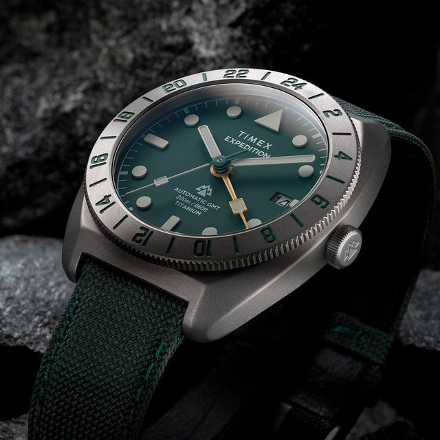 Close-up of Timex Expedition Pioneer Titanium Automatic GMT showing green dial, luminous markers, and GMT bezel.