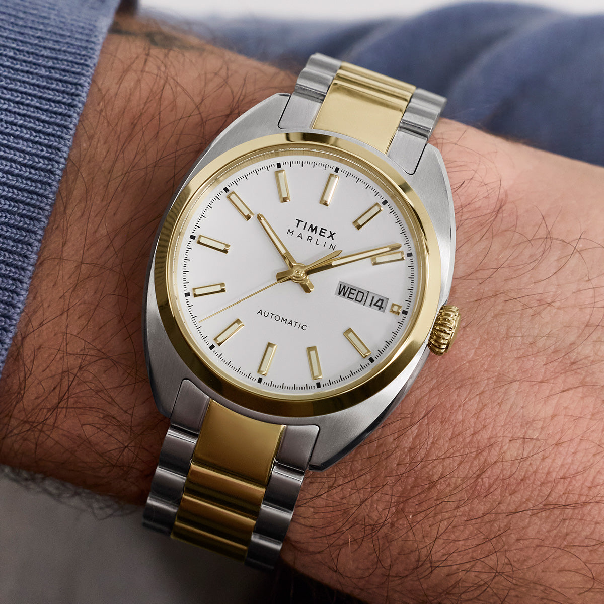 Timex Marlin® Draper Automatic two-tone watch worn on the wrist, showing a white dial, day-date window, and stainless steel and gold-tone bracelet.