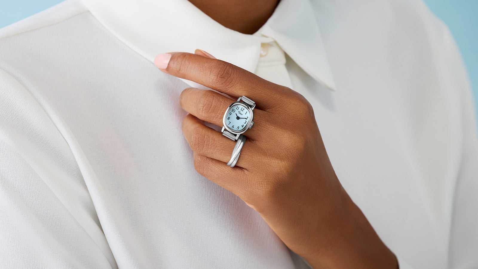 Timex Cavatina® Mini silver-tone watch with light blue dial worn as a ring on finger, paired with white blouse.