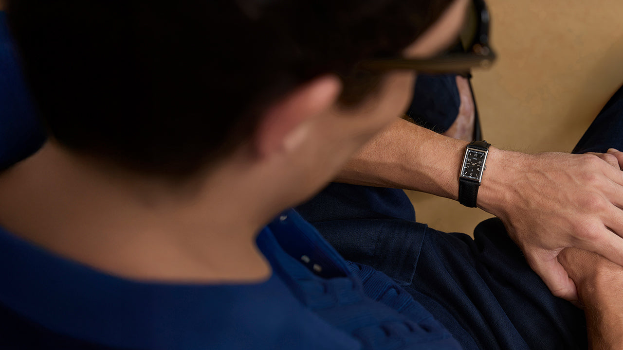 Top-down view of the Timex x Todd Snyder 1976 Lexington watch with a black dial and black leather strap worn with a blue outfit.