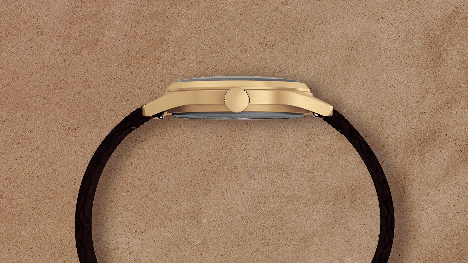 Side profile of Timex MK1 watch with gold-tone case and braided brown leather strap against a tan background.