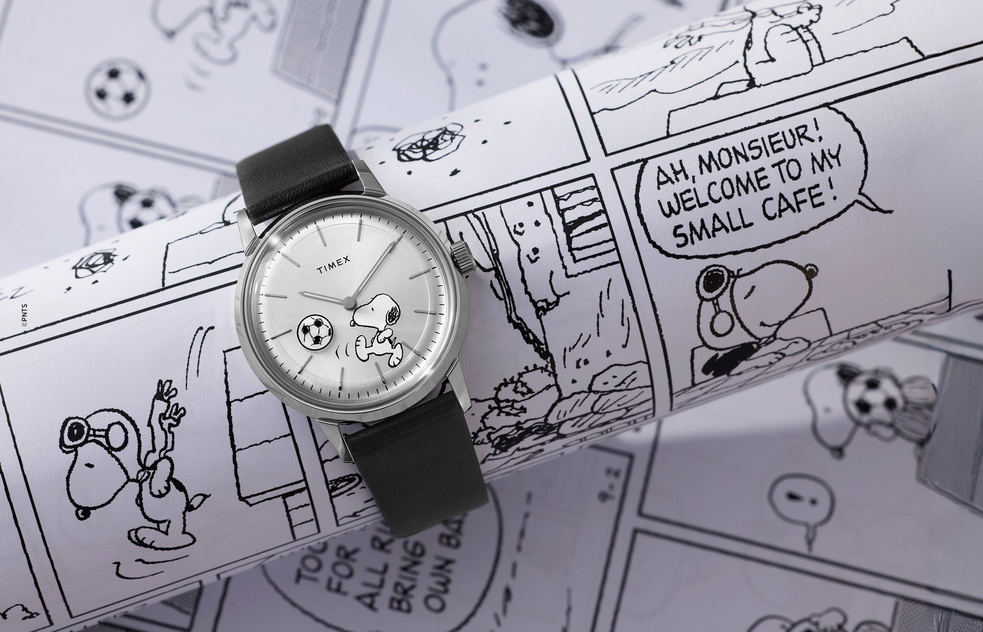 Timex Marlin Automatic x Peanuts watch with Snoopy soccer dial placed on black-and-white Peanuts comic strip background