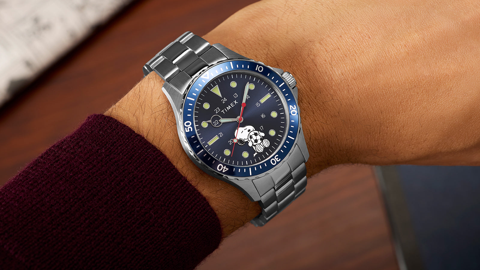 Angled view of Timex Navi Snoopy soccer watch on wrist showing blue dial and rotating bezel