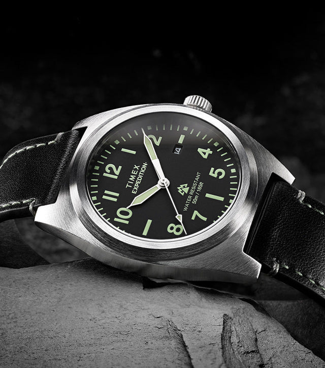Timex Expedition Capstone watch with black dial and leather strap resting on rocks