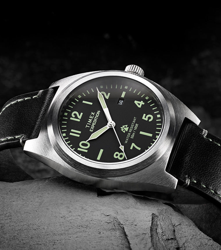Timex Expedition Capstone watch with black dial and leather strap resting on rocks