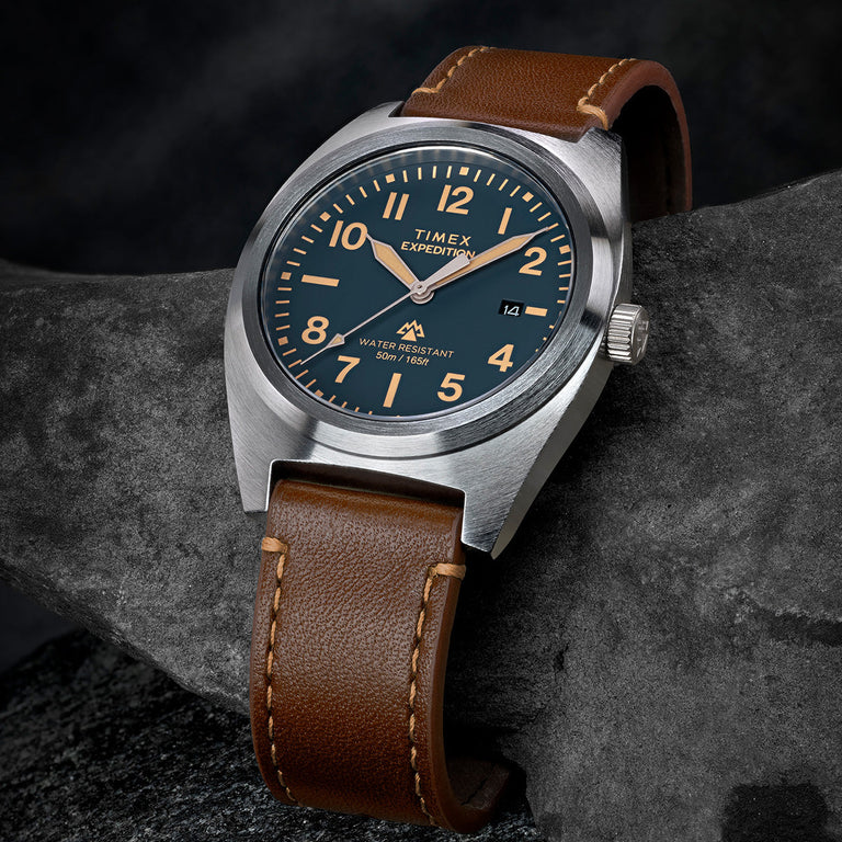 Timex Expedition Capstone watch with blue dial and brown leather strap on rock surface