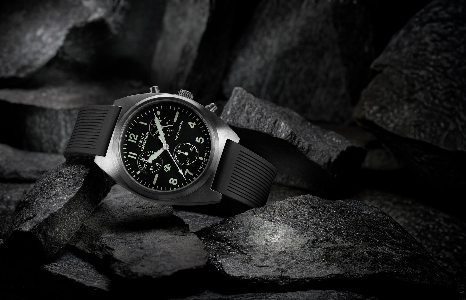 Timex Expedition Capstone Chronograph with black dial and rubber strap resting on rugged rocks