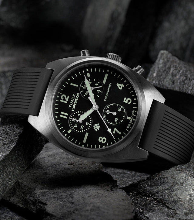 Timex Expedition Capstone Chronograph with black dial and rubber strap resting on rugged rocks