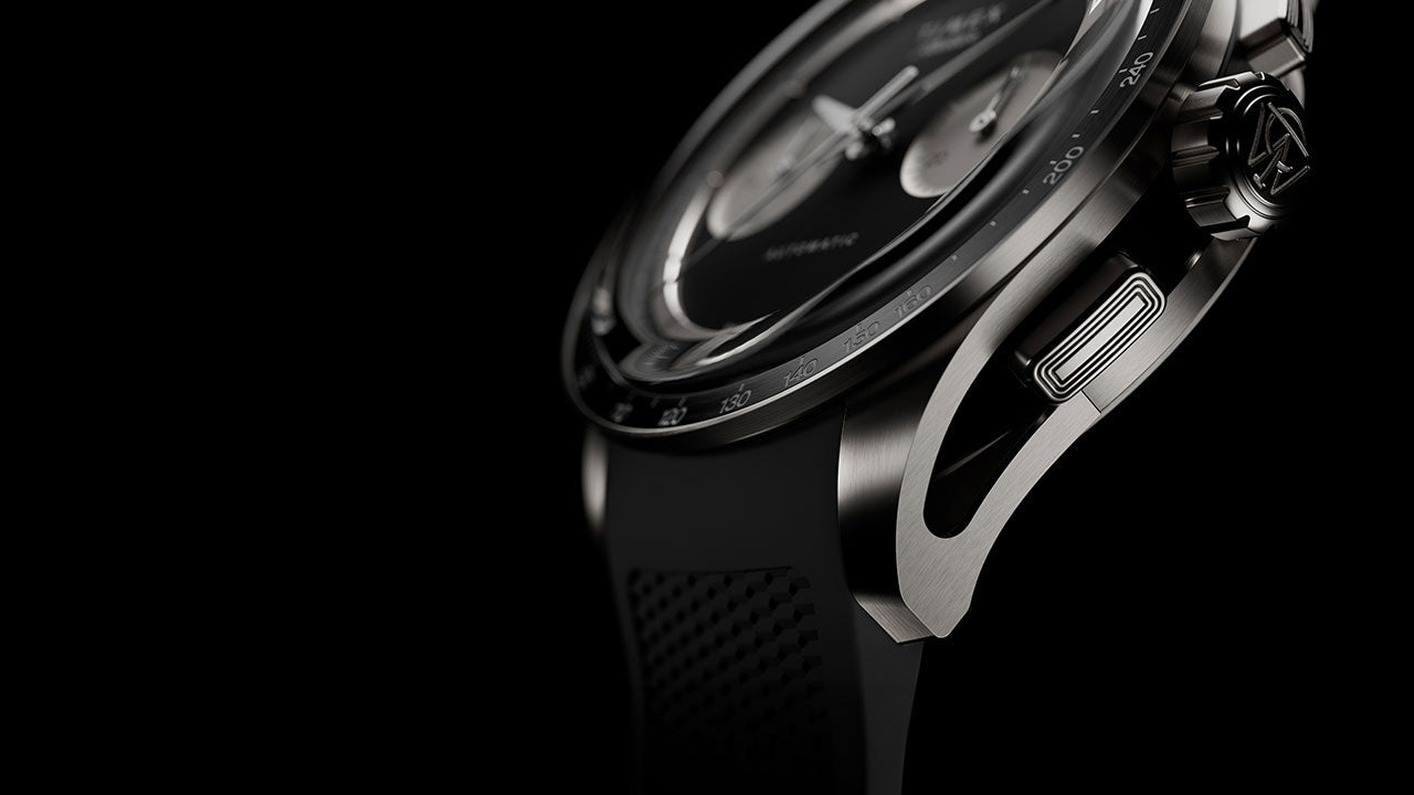 Side detail of Timex Atelier Chronograph Automatic Ti M1a titanium case with tachymeter bezel, crown, and black rubber strap