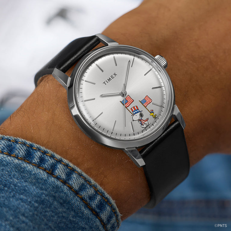 Timex Marlin Automatic Peanuts Americana watch worn on wrist with black leather strap and Snoopy flag illustration on dial