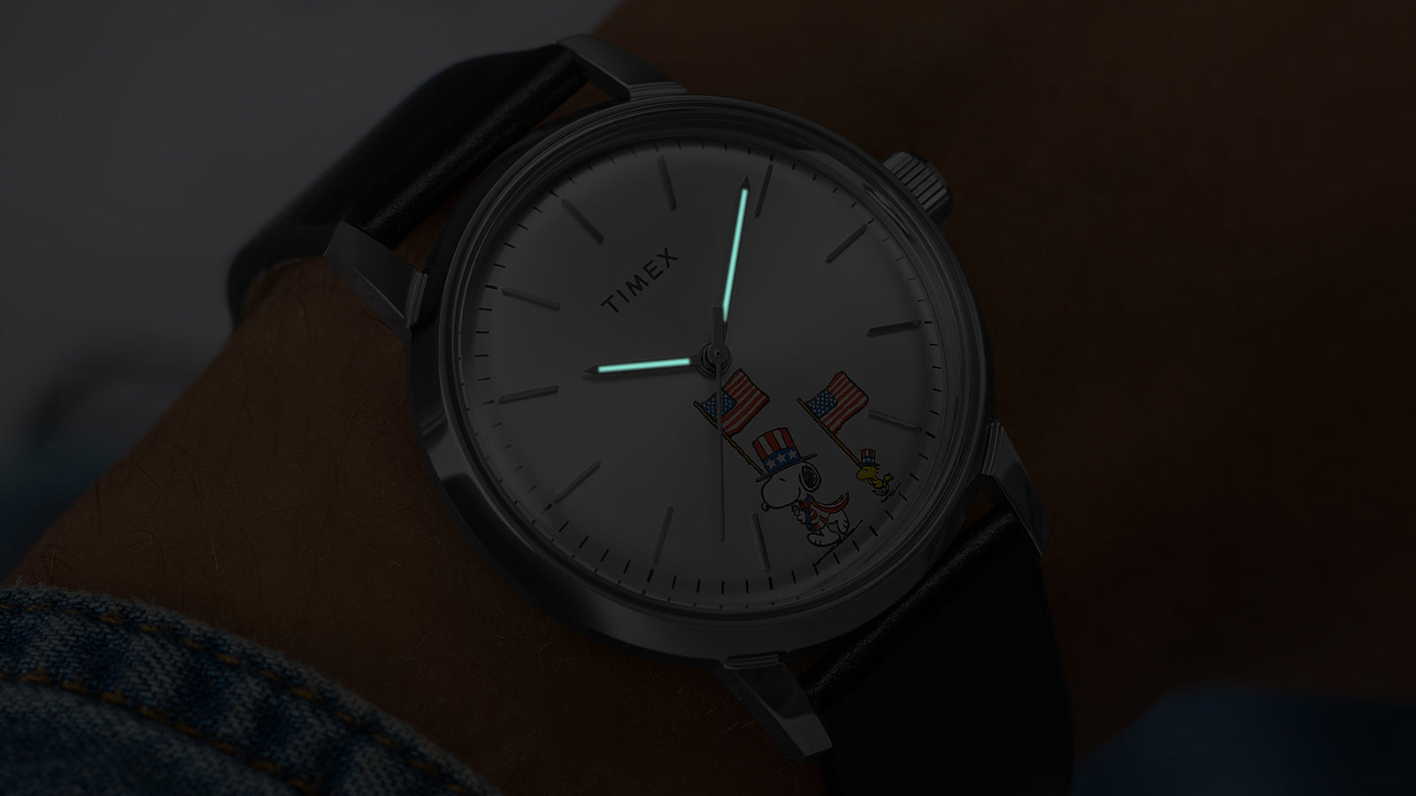 Timex Marlin Automatic Peanuts Americana watch on wrist in dark with illuminated hands and Snoopy dial graphic