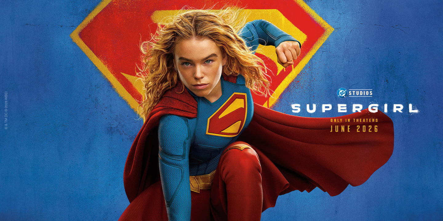 Supergirl promotional banner featuring the superhero in her iconic blue-and-red costume flying forward against a large Superman shield logo, with DC Studios Supergirl movie branding and June 2026 theatrical release information.