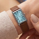 Close-up view of the Timex® 1976 Lexington Reissue Inspired watch on a wrist, highlighting the light blue dial, Roman numerals, and brown leather strap.