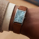 Timex® 1976 Lexington Reissue Inspired watch worn on a wrist, showcasing its rectangular silver-tone case, light blue dial, and brown leather strap.