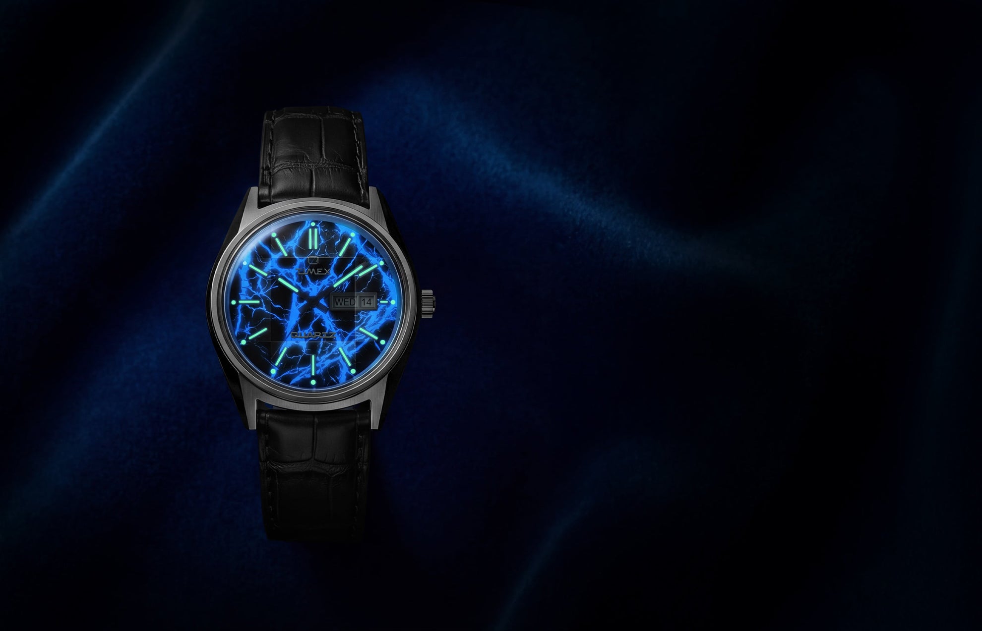 Q Timex Blue Vega watch glowing in the dark with illuminated blue lightning dial and lume hour markers on black leather strap