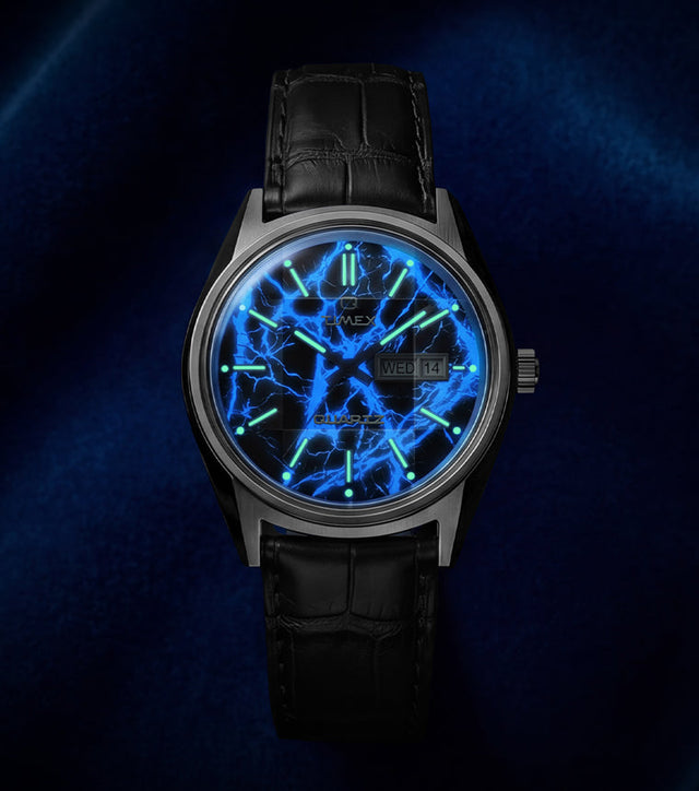 Q Timex Blue Vega watch glowing in the dark with illuminated blue lightning dial and lume hour markers on black leather strap
