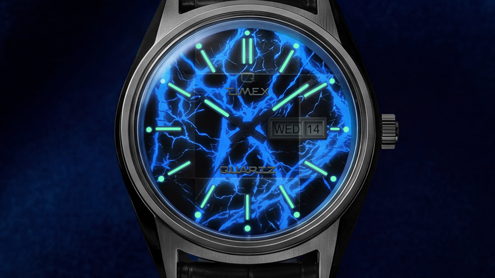 Close-up macro of Q Timex Blue Vega dial with luminous markers, day-date window, and electric blue lightning-inspired design