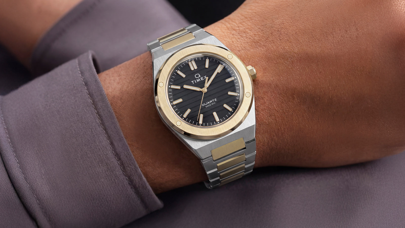 Close-up of the Timex Q Marbella two-tone stainless steel watch with a black dial worn on the wrist.