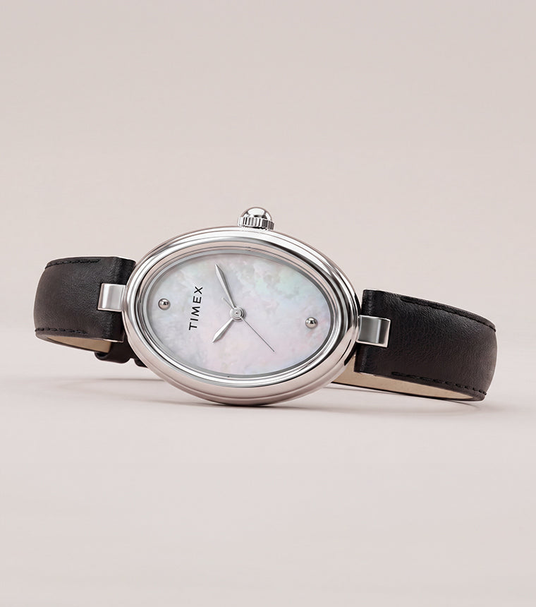 Timex Cavatina® Luxe watch with a silver-tone oval case, mother-of-pearl dial, and black leather strap displayed on a soft neutral background.