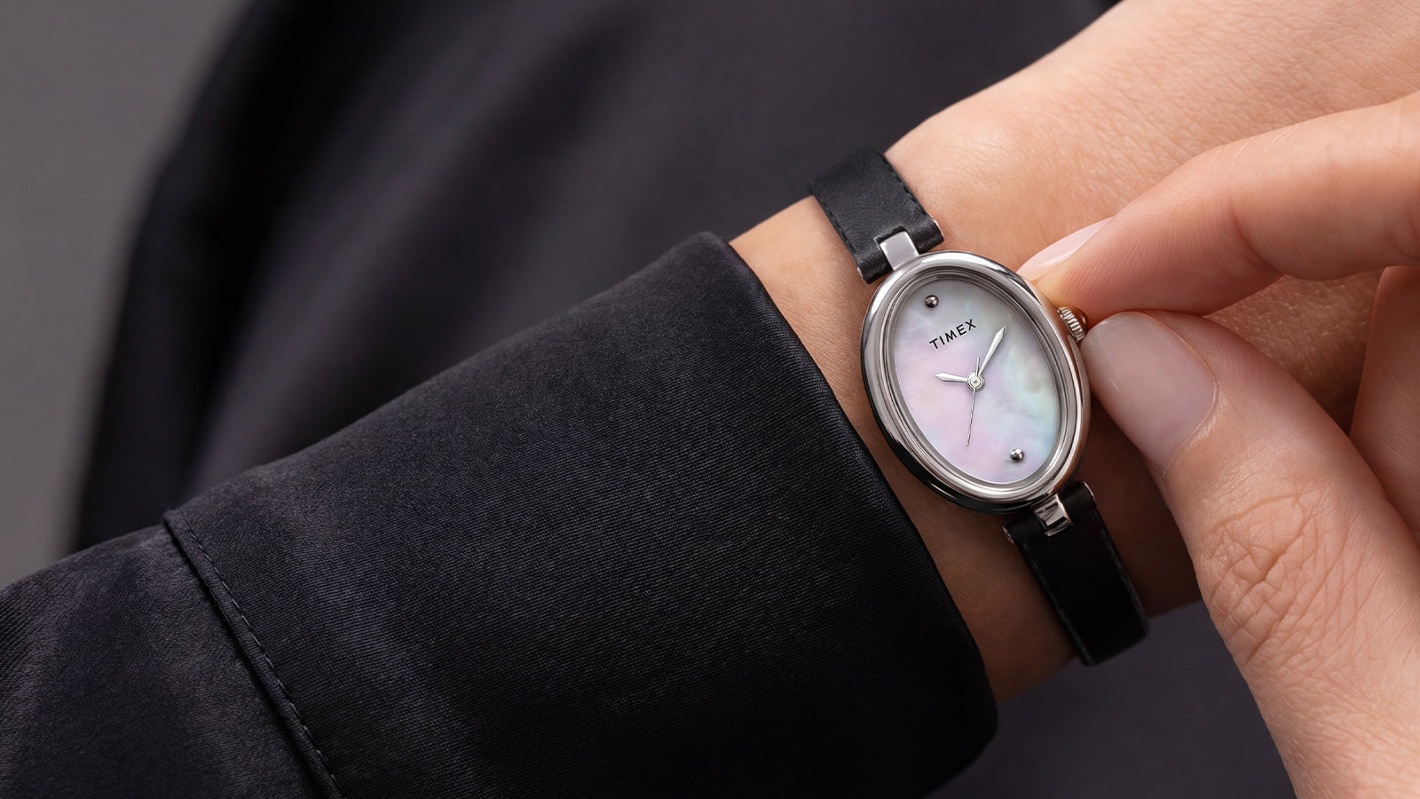 Close-up of the Timex Cavatina® Luxe with a silver-tone oval case, mother-of-pearl dial, and black leather strap worn on the wrist.