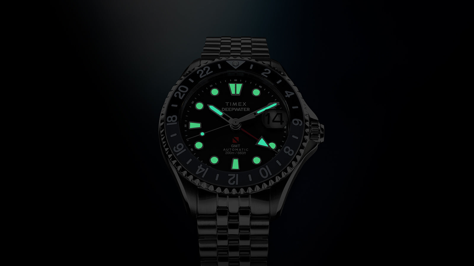 Timex Deepwater Meridian 200 Automatic GMT watch in low light with Super-Luminova® hands and hour markers glowing for enhanced nighttime visibility.