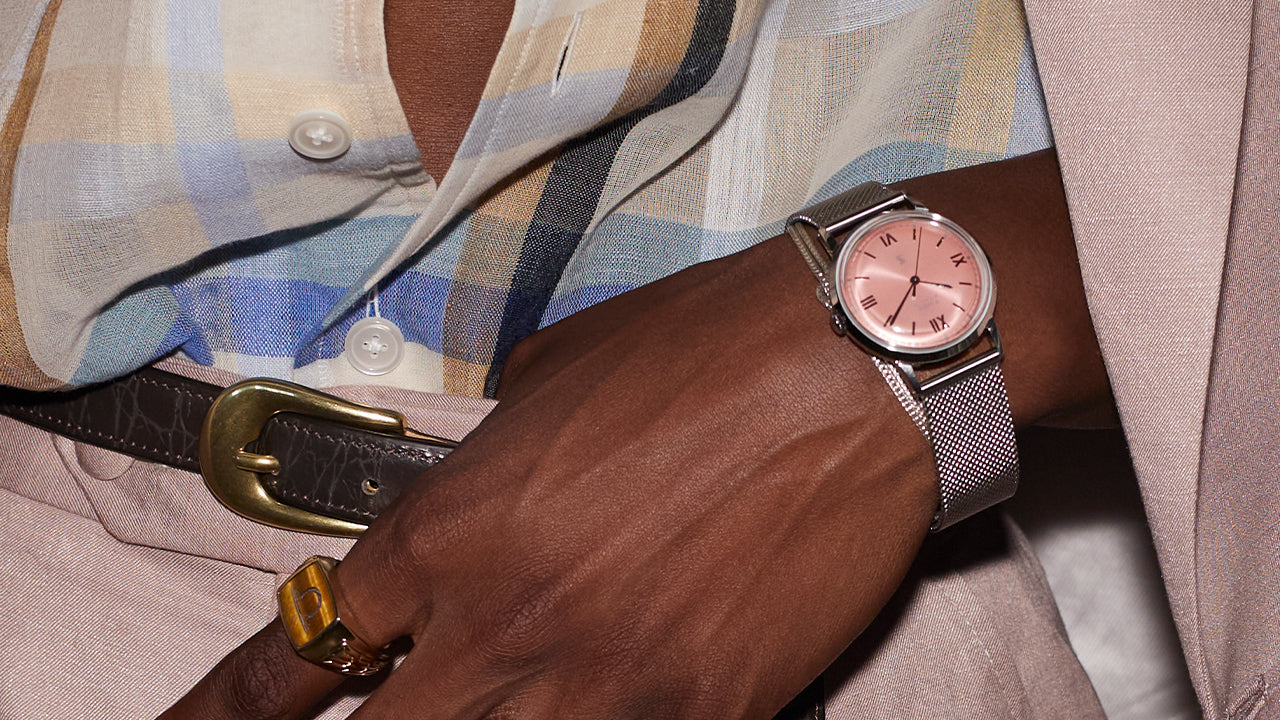 Todd Snyder x Timex Marlin® Mesh watch with a pink dial and stainless steel mesh bracelet worn with a pastel suit, patterned shirt, and statement ring.