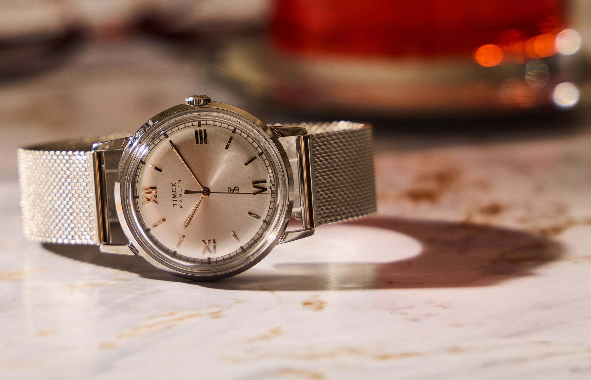 Todd Snyder x Timex Marlin® Mesh watch with a silver sunray dial and stainless steel mesh bracelet displayed on a marble table.