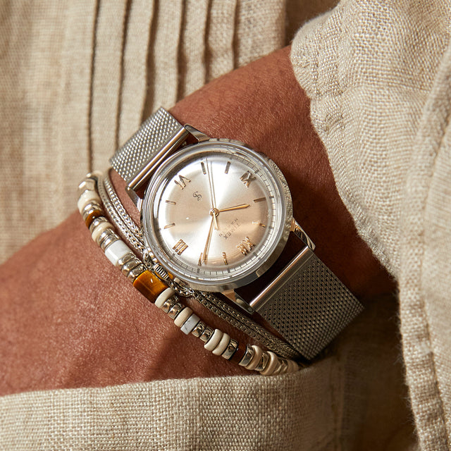 Todd Snyder x Timex Marlin® Mesh watch with a silver sunray dial and stainless steel mesh bracelet paired with layered beaded bracelets.