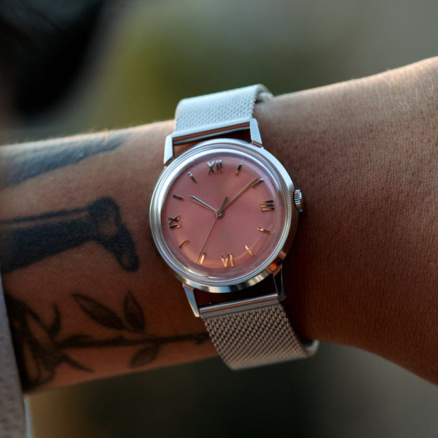 Close-up of the Todd Snyder x Timex Marlin® Mesh watch with a pink dial and stainless steel mesh bracelet worn on the wrist.