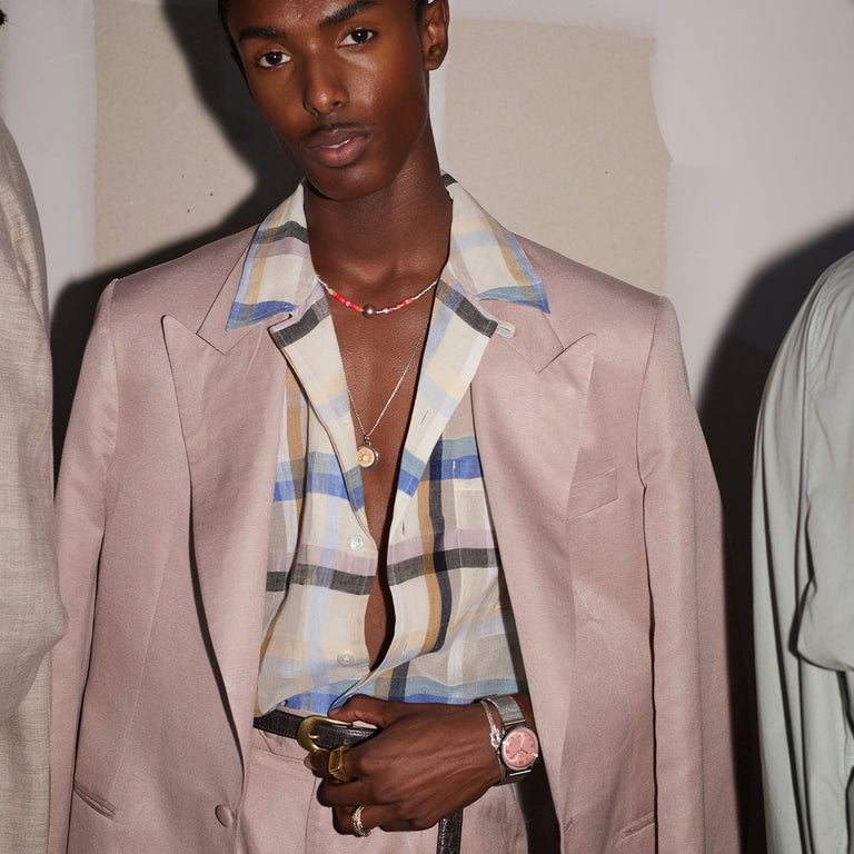 Person wearing the Todd Snyder x Timex Marlin® Mesh watch with a pink dial, paired with a pastel suit and plaid shirt.