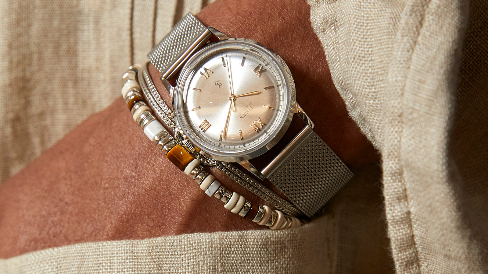Detailed view of the Todd Snyder x Timex Marlin® Mesh watch featuring a silver sunray dial, Roman numeral hour markers, and a stainless steel mesh bracelet.