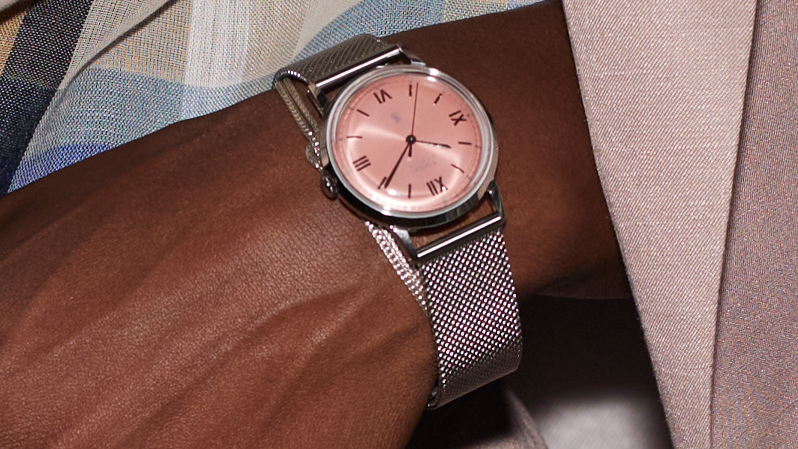 Close-up of the Todd Snyder x Timex Marlin® Mesh watch with a pink dial worn with a pastel suit and patterned shirt.