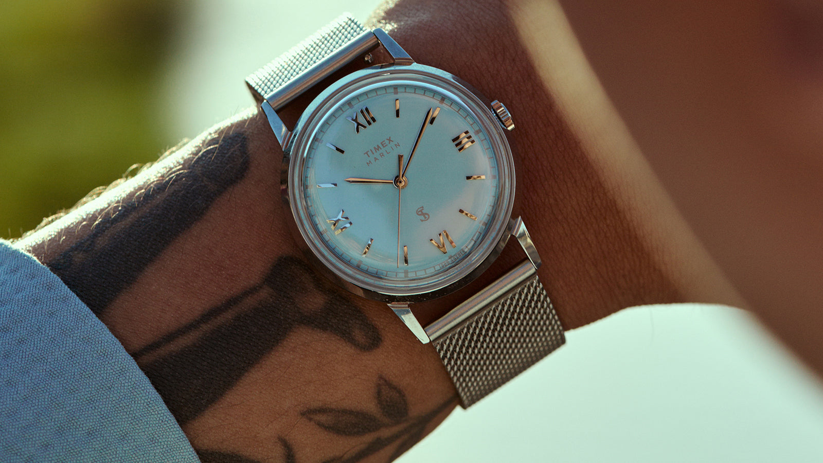 Detailed view of the Todd Snyder x Timex Marlin® Mesh watch featuring a light blue dial, Roman numeral markers, and a stainless steel mesh bracelet on the wrist.