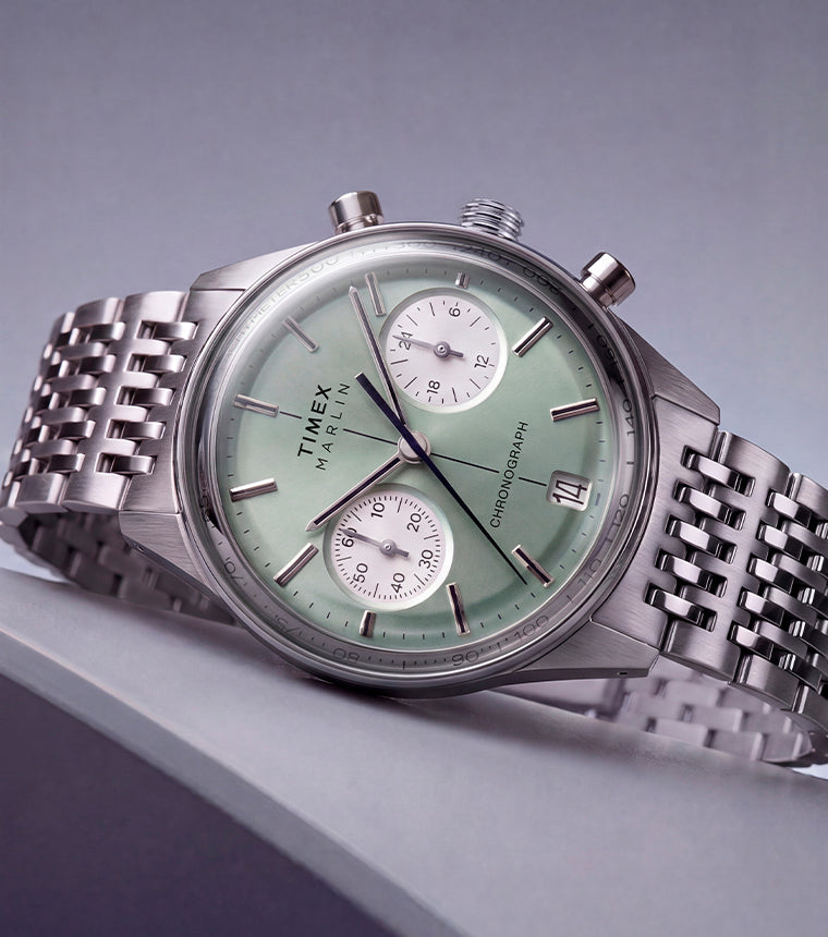 Timex Marlin® Jet Chronograph with a green dial and stainless-steel bracelet displayed on an angled surface.