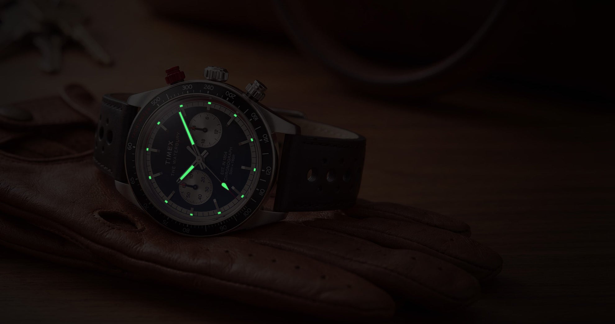 Timex Waterbury Heritage Chronograph with luminous hands and hour markers glowing in low light.