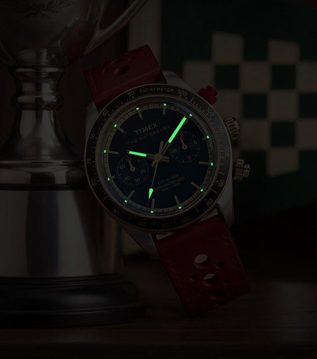 Waterbury Heritage Chronograph in a dark setting, highlighting the green luminous hands and hour markers on the blue dial.