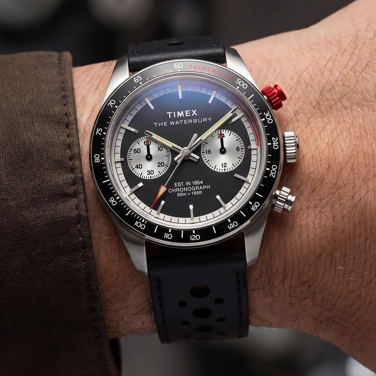 Timex Waterbury Heritage Chronograph with a black leather racing strap and panda-style chronograph dial worn on the wrist.