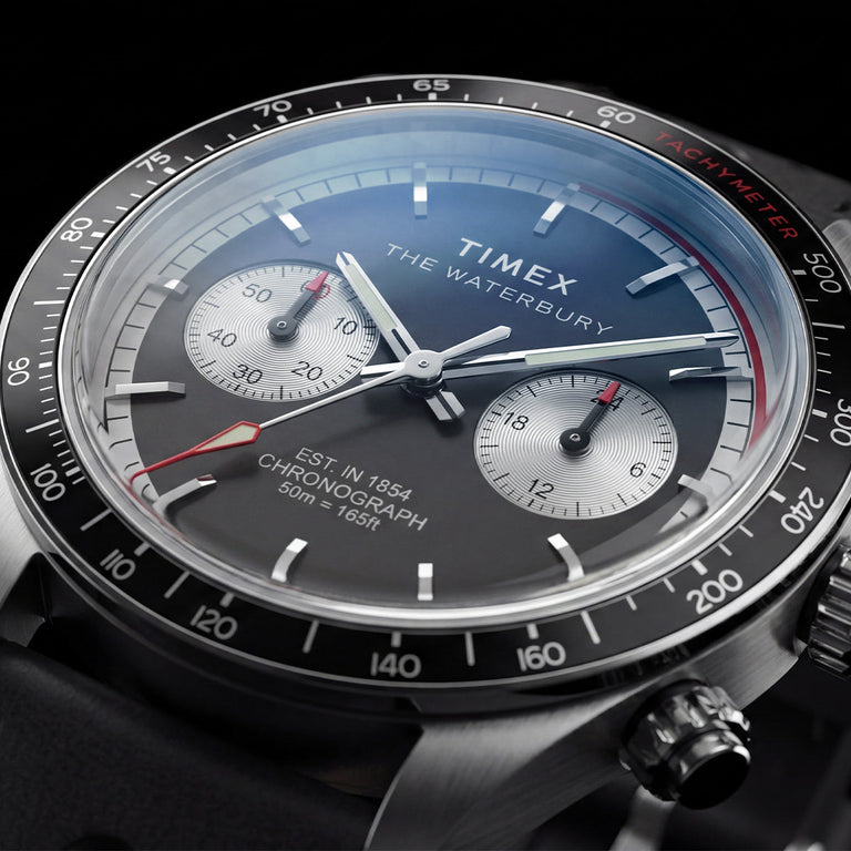 Close-up of the Timex Waterbury Heritage Chronograph featuring a black and silver panda-style dial, dual chronograph sub-dials, tachymeter bezel, and red chronograph accents.