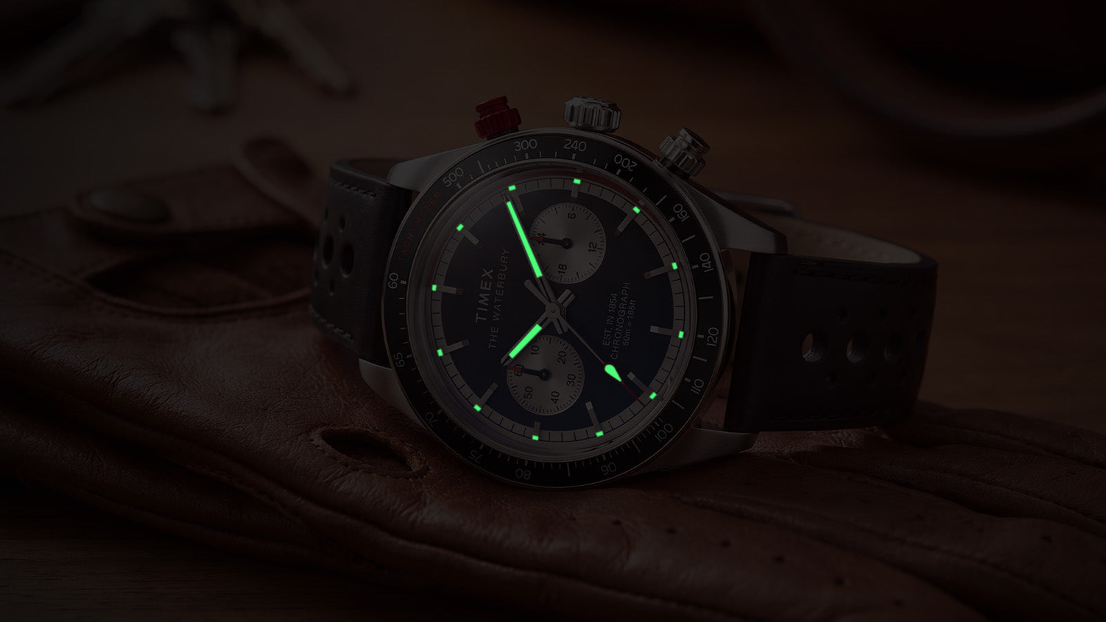 Timex Waterbury Heritage Chronograph with luminous hands and hour markers glowing in low light.