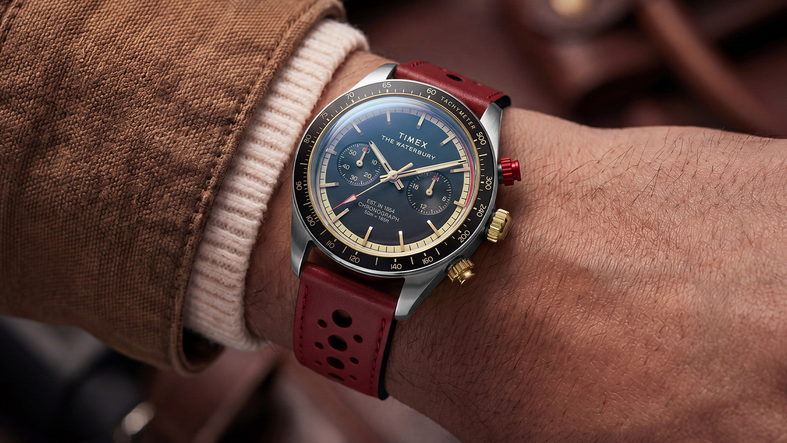 Close-up of the Timex Waterbury Heritage Chronograph with a red perforated leather racing strap and blue chronograph dial worn on the wrist.