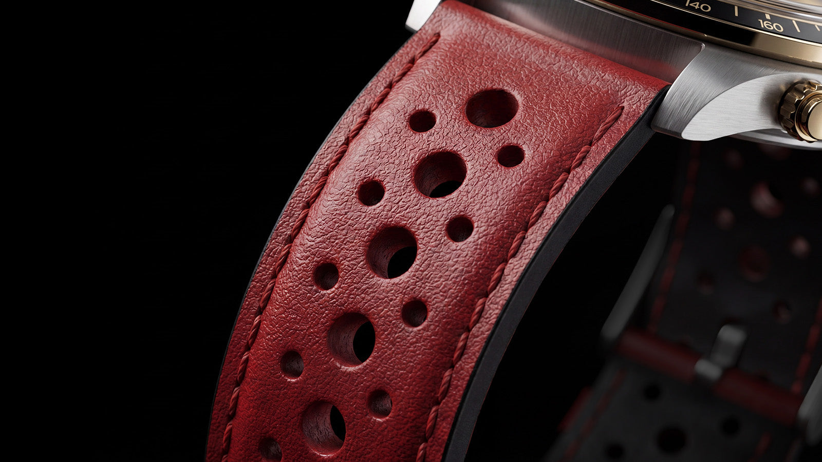 Close-up of the Timex Waterbury Heritage Chronograph red perforated leather racing strap attached to the stainless steel case.